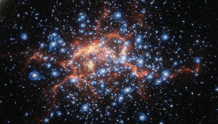 Плотное скопление молодых и ярких галактик в глубоком космосе, пространство между которыми заполнено раскаленным светящимся газом.